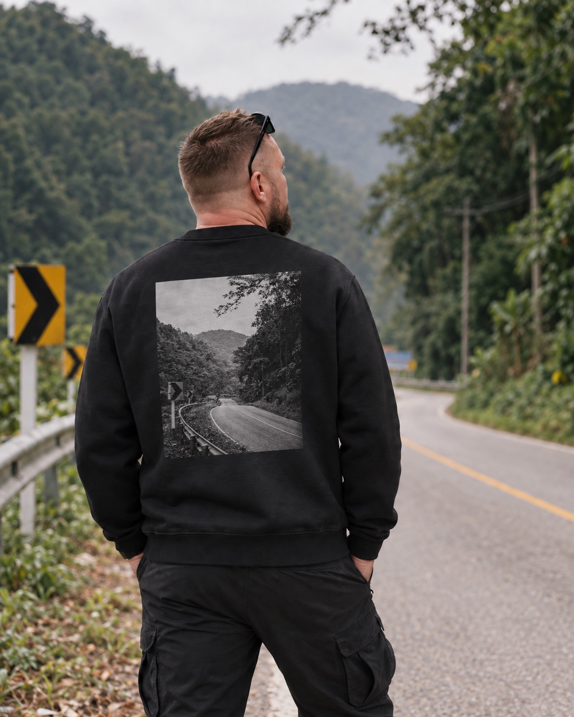 Matti seen from behind wearing the sweatshirt with a 35 × 45 cm monochrome photograph of a winding mountain road on the back
